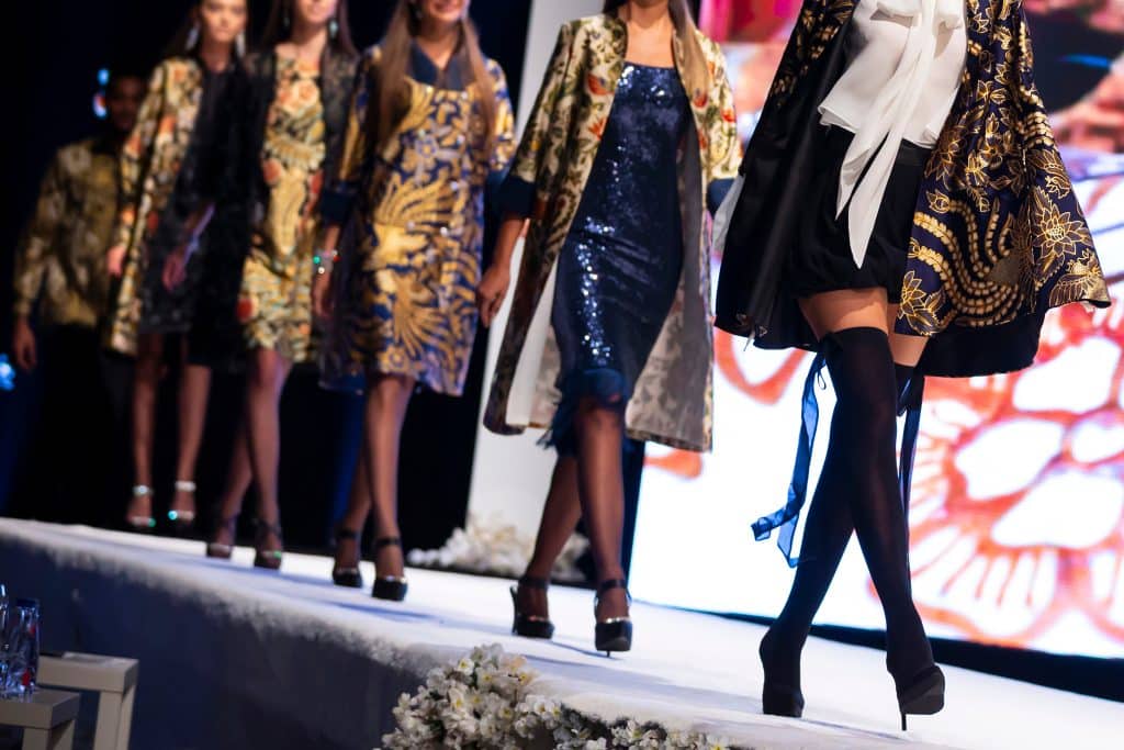 Image of five fashion models walking on a runway.