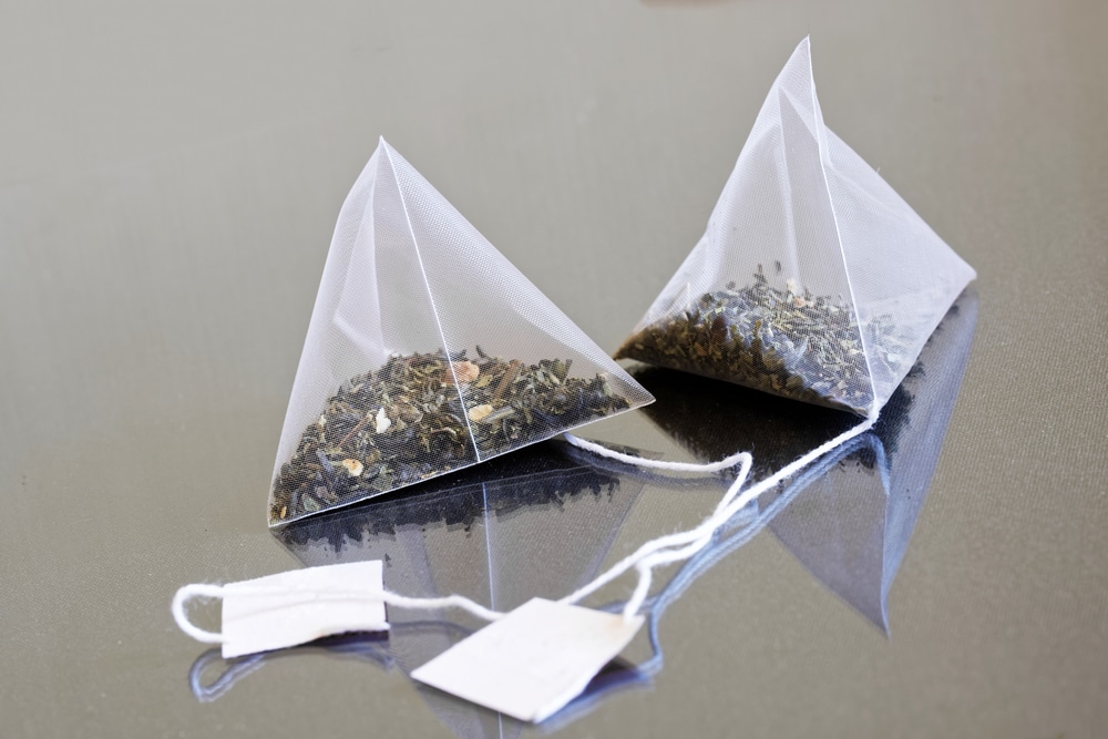White pyramid tea bags containing green tea.