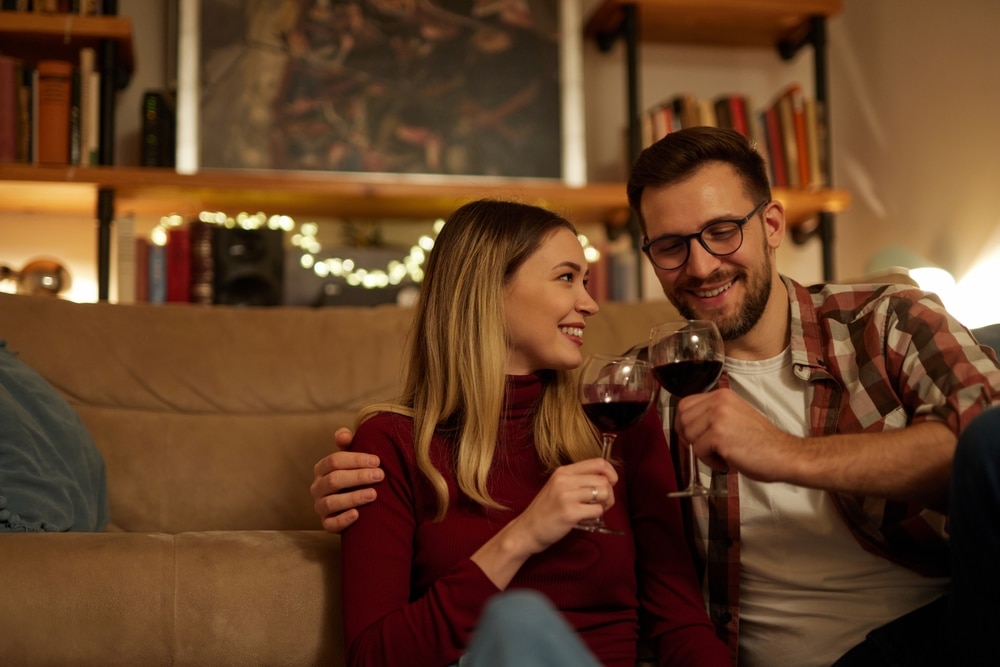 A couple holding red wine in their living room