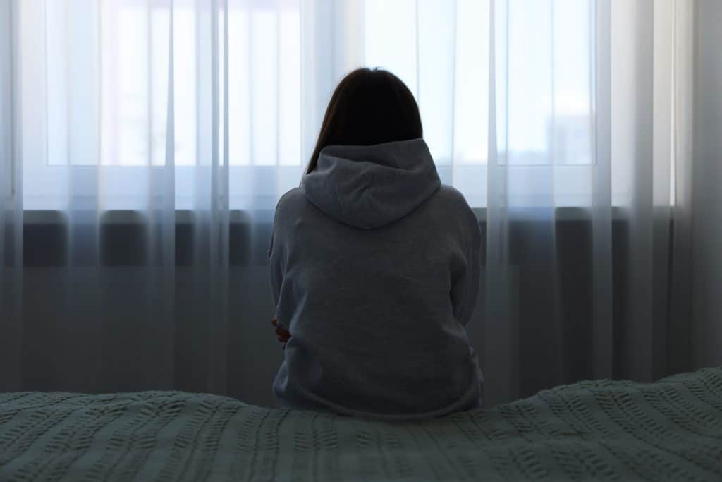 Woman sits alone in a dark room
