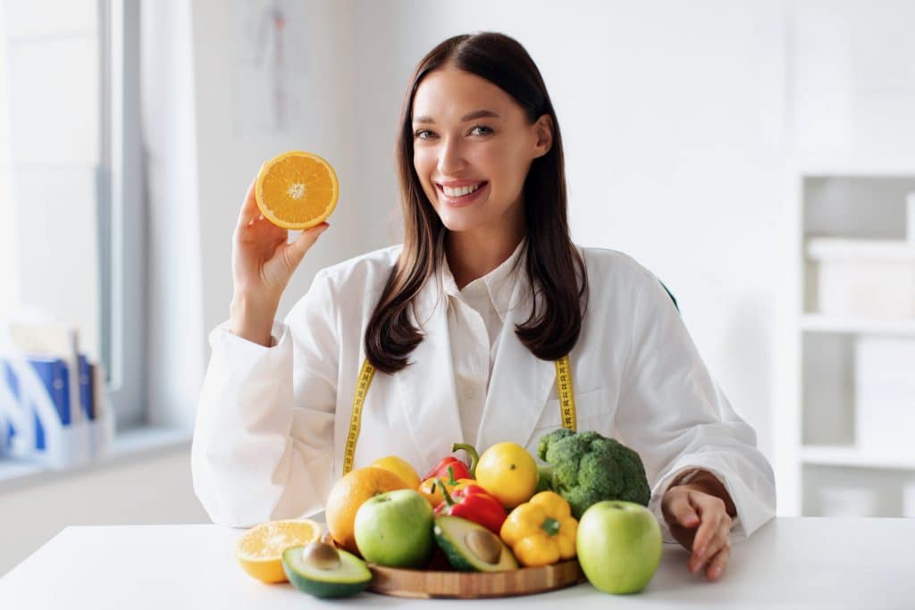 Nutritionist with a bowl of fruits and vegetables in front of her.
