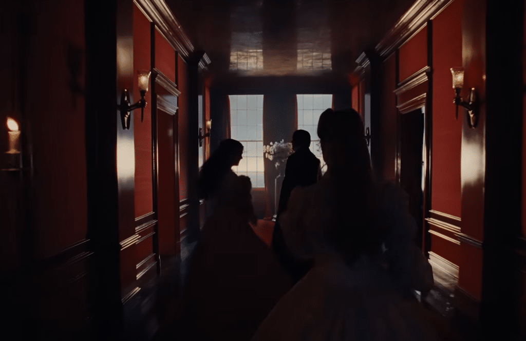 Isabella and Edgar Linton lead Catherine through a bright red hallway in Thrushcross Grange.