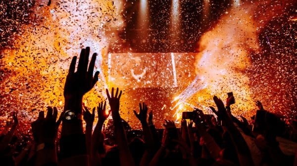 Bright lights during a concert with crowd lifting their arms up