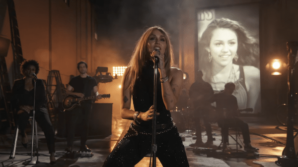 Miley Cyrus singing an emotional song while pictures of her younger self flash behind.