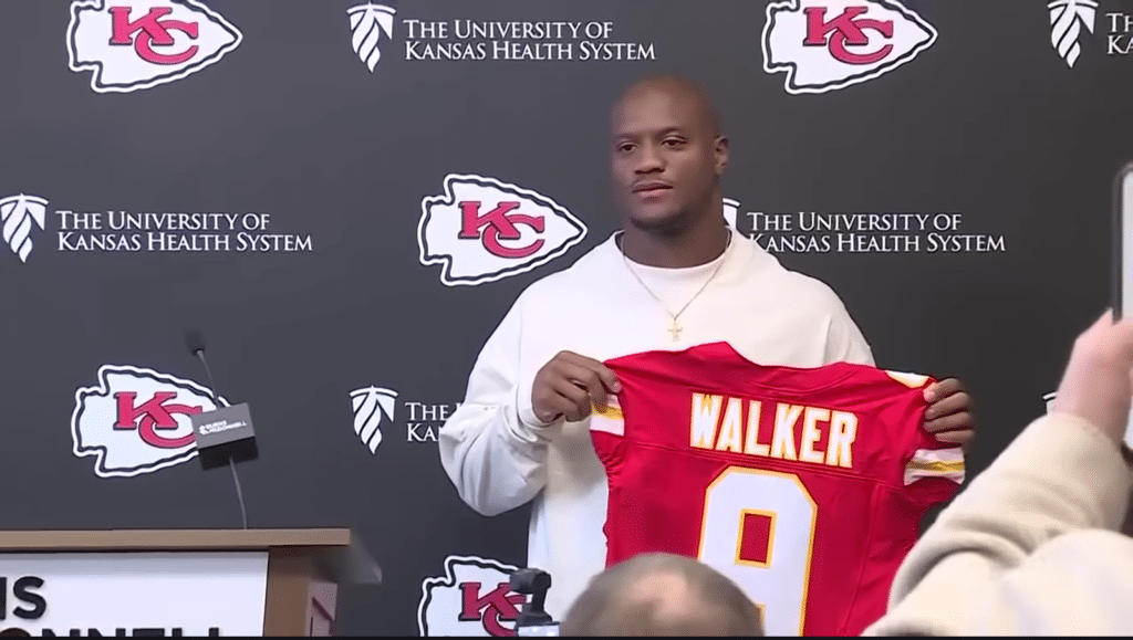 Kenneth Walker III poses with his Kansas City Chiefs jersey at his introductory press conference.