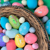 The image shows a basket of decorated eggs with more eggs on a table top around it.