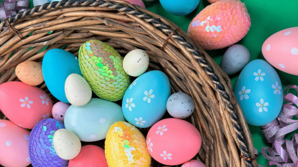 The image shows a basket of decorated eggs with more eggs on a table top around it.