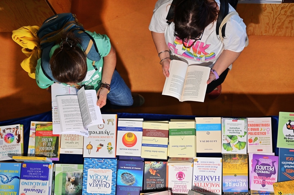 Two people reading books by a display table