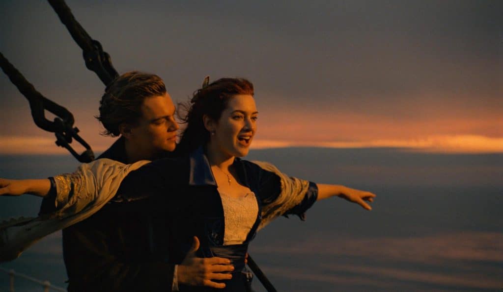The image is a still from Titanic 1994, featuring Jack and Rose on the helm of a ship.
