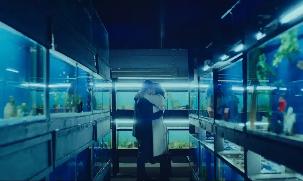 Jack O'Connell as Jude and Olivia Cooke as Emma kissing between fish tanks in "Little Fish." Courtesy of AP.