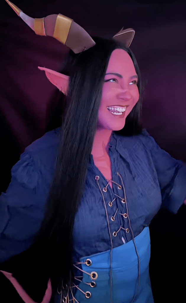 A woman in cosplay wearing medieval clothes, elf ears, and horns.