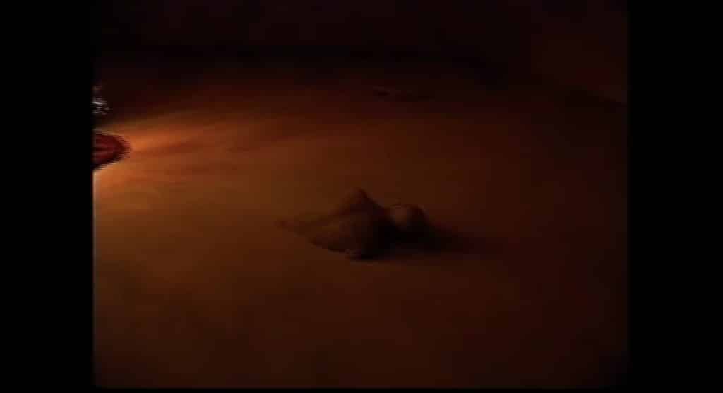A much darker photo of The Backrooms where it appears an individual is phasing through the floor.