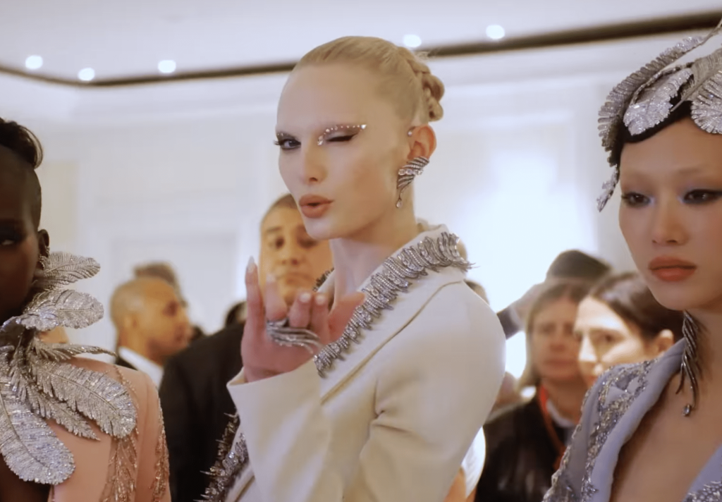 Alex Cosani blowing a kiss to the camera in a white Swarovski