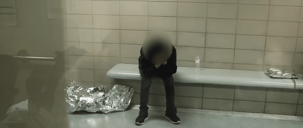 Man sits in a tiled room with scattered aluminum sheets.