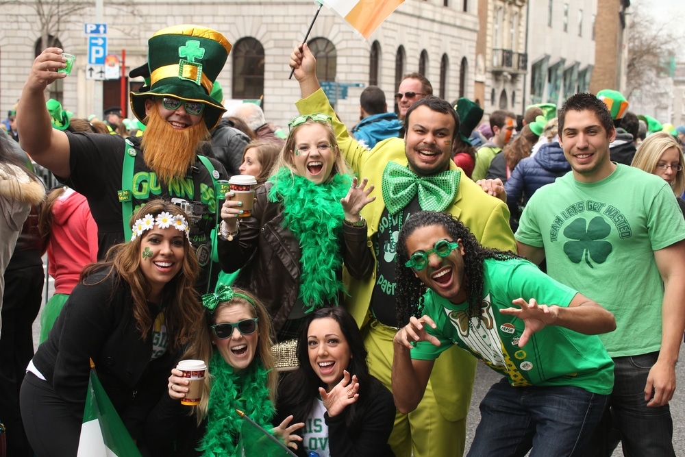 Friend's celebrating Saint Patrick's Day at a parade dressed in festive attire and posing with beer