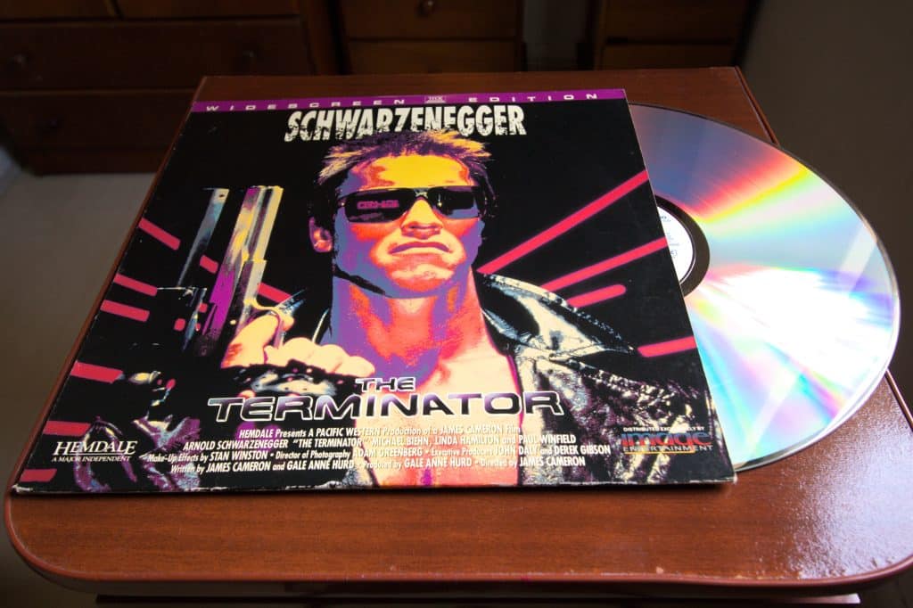 A LaserDisc of the movie "The Terminator" sitting, slightly out if it's case on a brown tabletop.