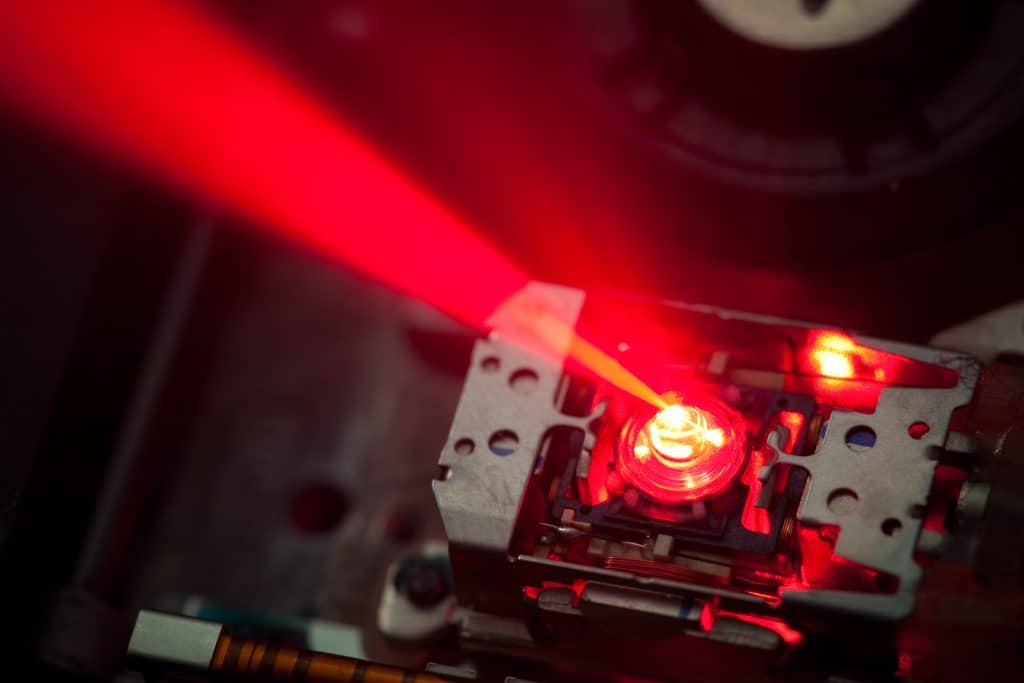 A close up shot of the laser technology used to make a DVD. The laser is shining bright red across the image.