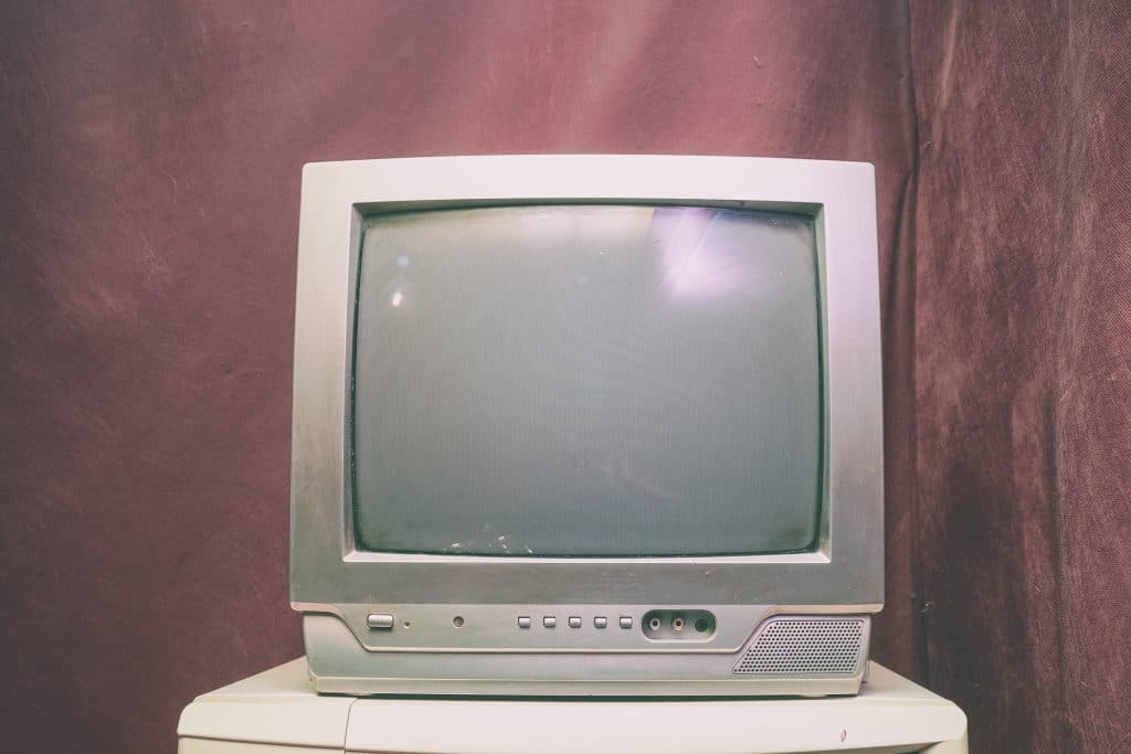 A grey box television sits on a white tabletop