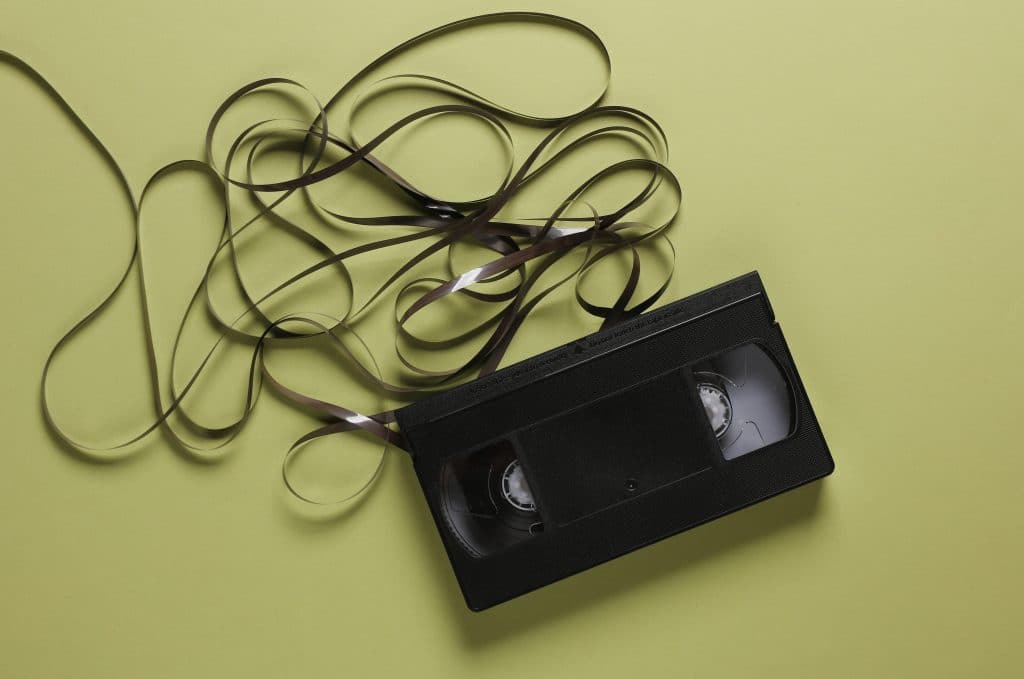 A VHS tape against a light green background. The tape has been pulled out of the player, and is lying loose on the surface.