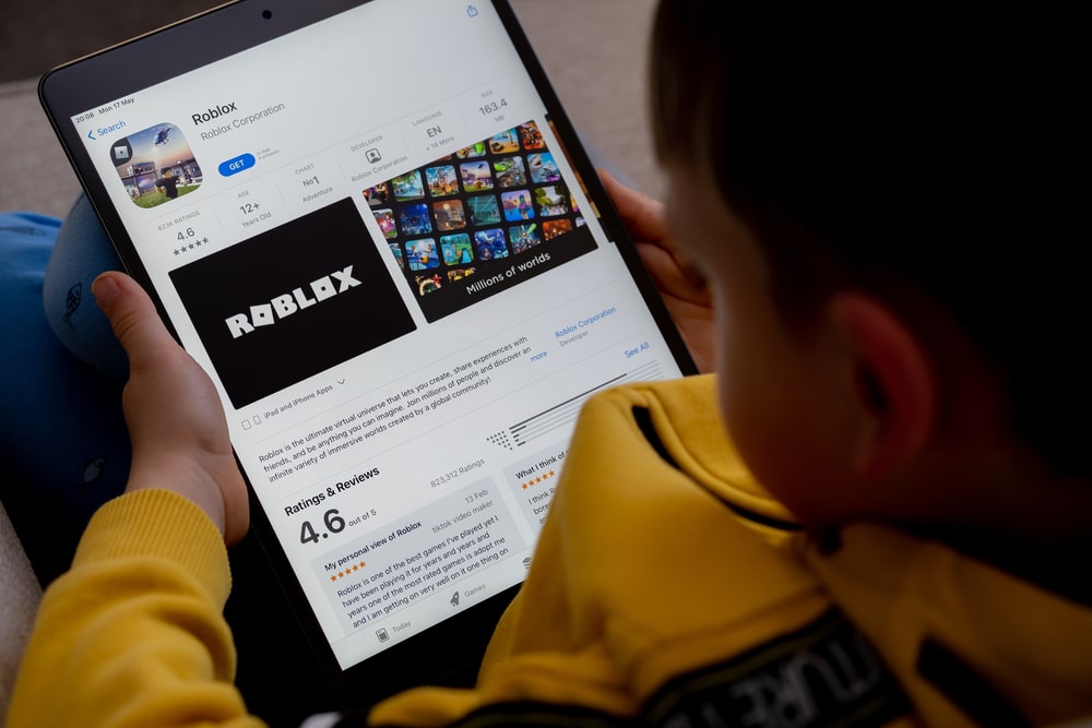 Over the shoulder of a child downloading Roblox from the app store on their tablet.