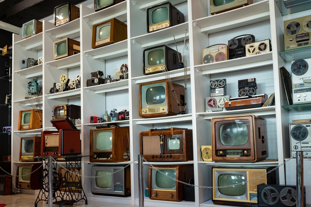 A large store shelf stocked full of some of the earliest television sets.