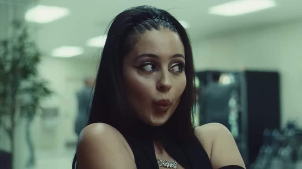 Maddy Perez pouting with her hair pulled back, wearing bold eyeliner and a dark brown lipstick.