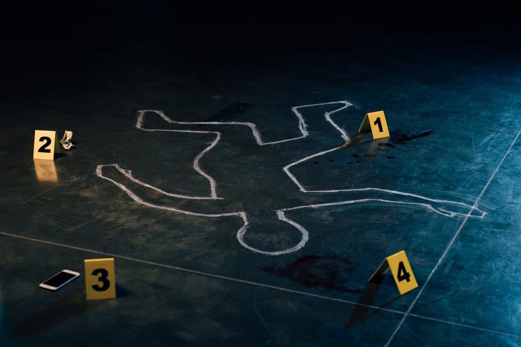 A chalk drawing of a body on a metal floor