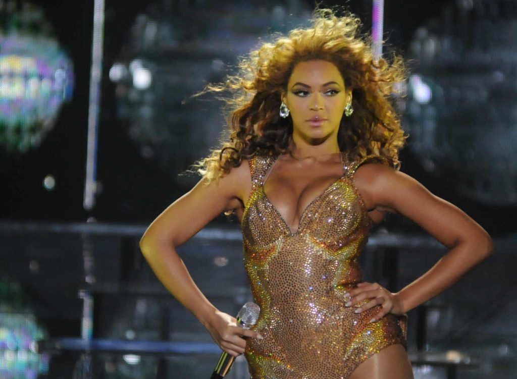 Photo of Beyonce posed with hands on her hips in gold, sparkling leotard.