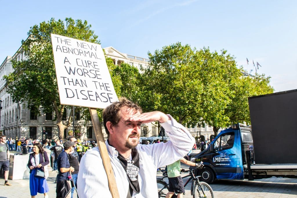 Man carries sign stating: "The New Abnormal: A Cure Worse Than The Disease."