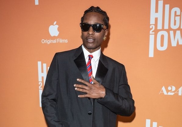 A$AP Rocky in black tux and sunglasses. Left hand covers chest to show off rings