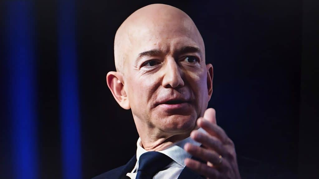 Photo of Jeff Bezos in black tux speaking in a conference as he gestures with his hand