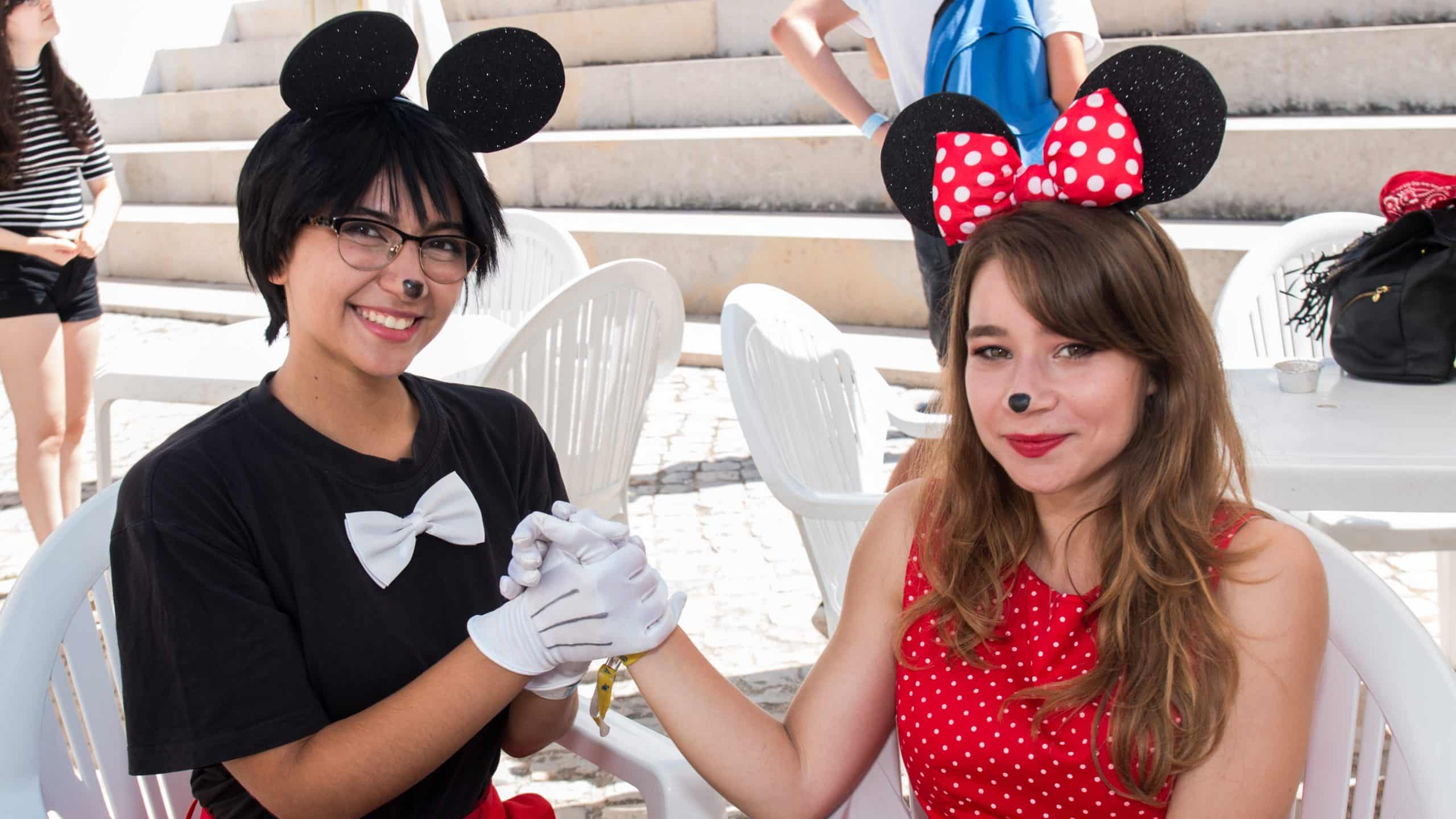 Two people dressed as Minnie and Mickey Mouse holding hands