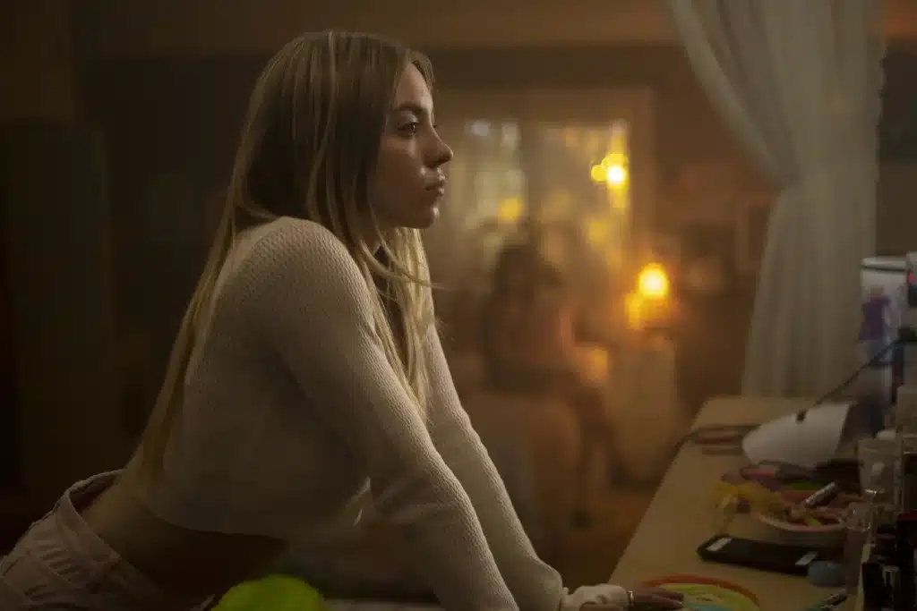 Cassie Howard leaning against her desk, looking straight into the mirror ahead of her with a straight face.