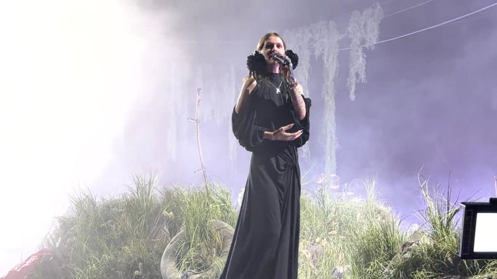 Cain performing in all-black dress with bushes behind her and blaring stage lighting at Coachella 2026 festival