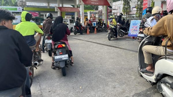 Many motorbikes waiting in line at the gas station.