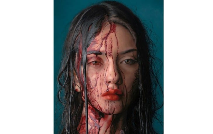 Image of a woman's face, covered in blood. A partial screenshot of a larger oil painting.