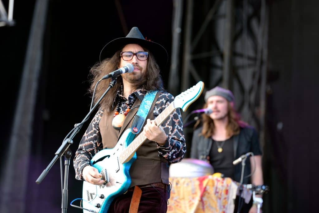 Sean Ono Lennon looks down at his guitar neck as he plays bass.
