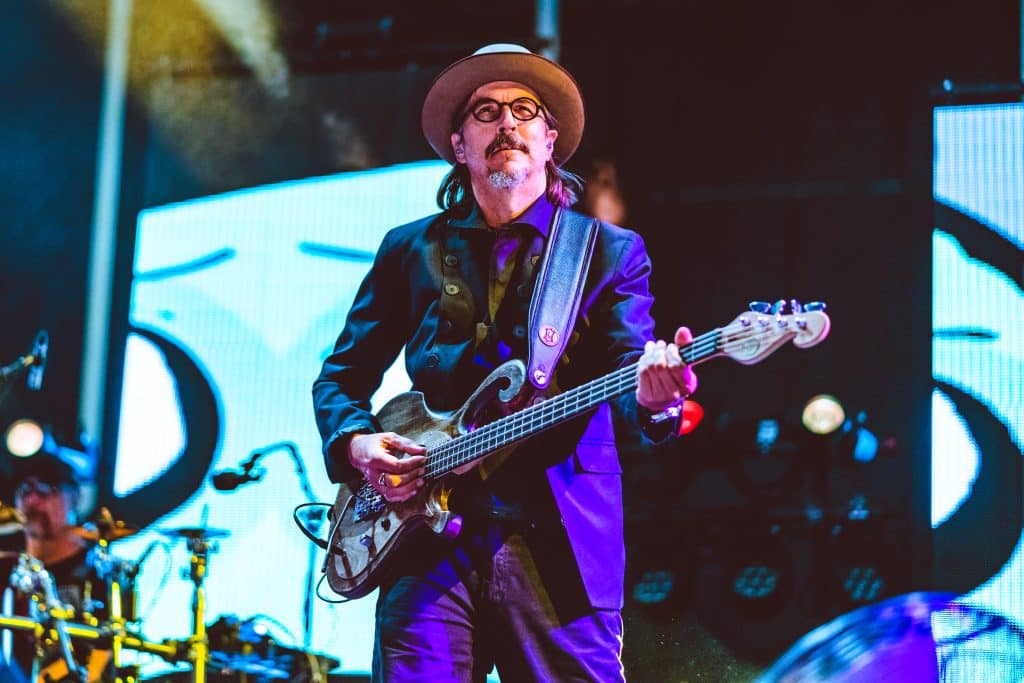 Les Claypool plays guitar on stage. He's shaded in purple stage lighting, and looks upwards.
Key word: Claypool Lennon Delirium
