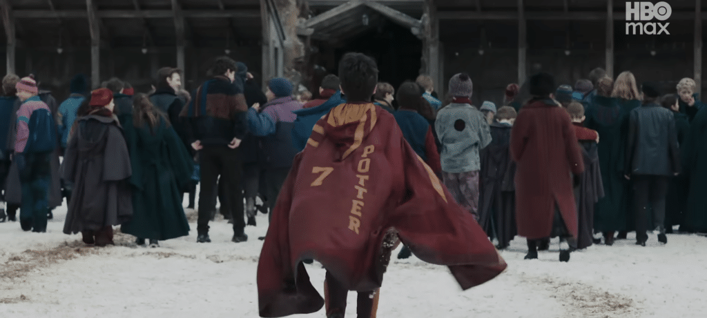 Harry walking toward the Quidditch pitch draped in his uniform.