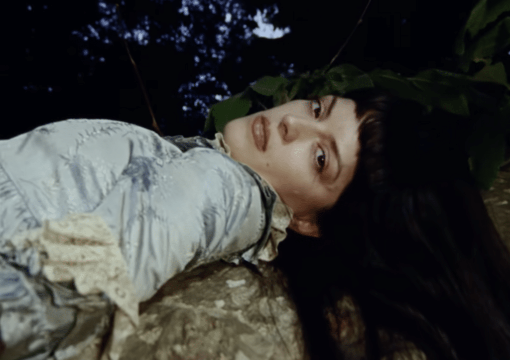 María Zardoya in Message 2 music video, looking into the camera on a rock.