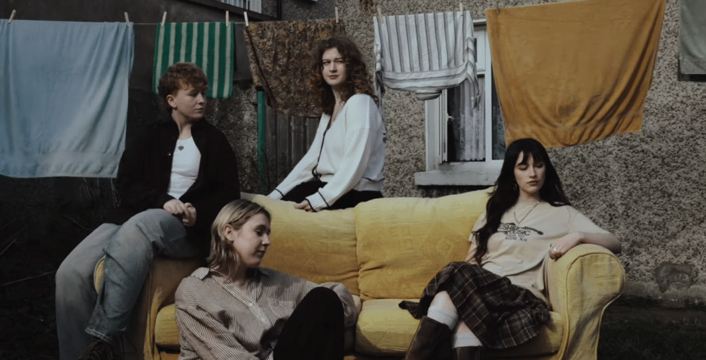 Members of Florence Road sat on a yellow couch in the music video for Heavy.