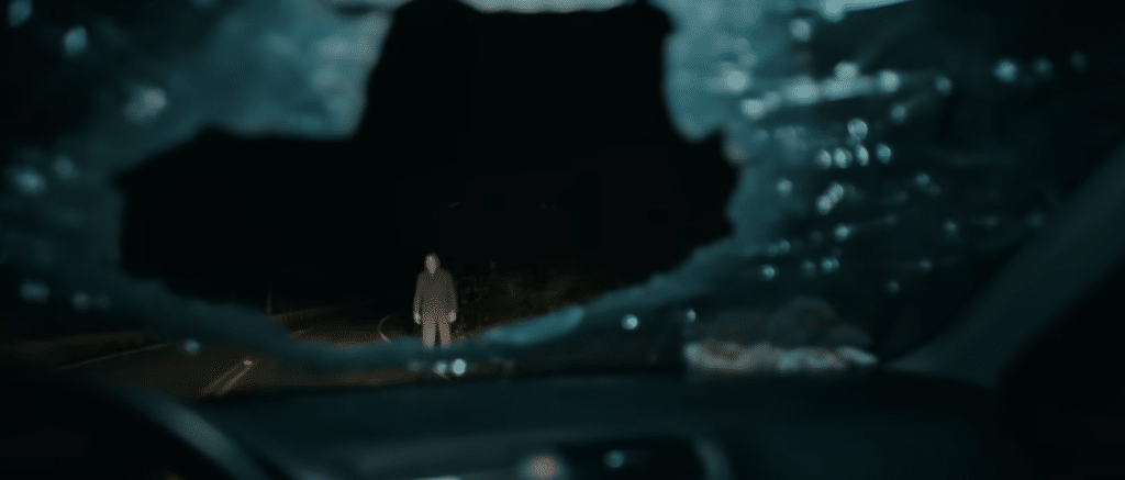 Image from 'Passenger' movie of man standing ominously outside shattered car window