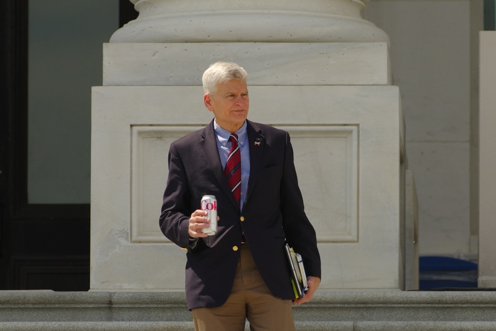 Senator Bill Cassidy photographed walking out the U.S. Capitol, walking at a leisurely pace with a diet coke in hand.