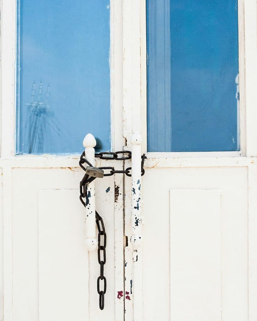 A pair of white doors locked by a chain and padlock.