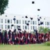 A collection of college students in their caps and gowns, throwing their caps at graduation.