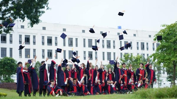 A collection of college students in their caps and gowns, throwing their caps at graduation.