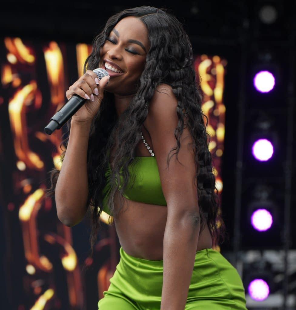 Coco Jones with microphone, performing on stage
