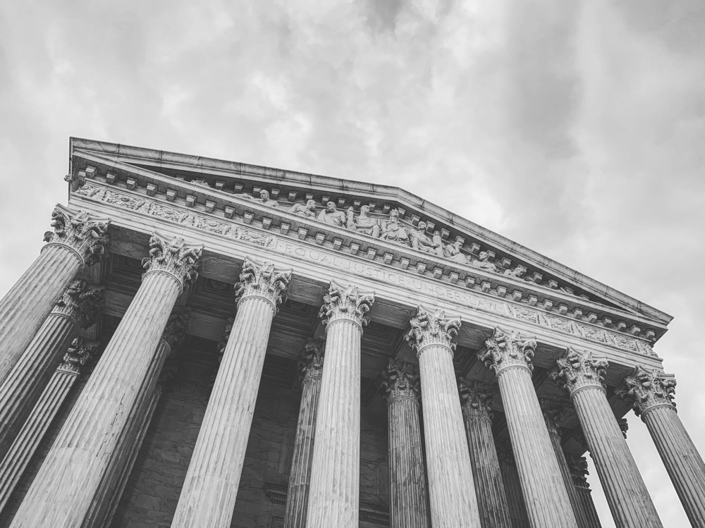 Supreme Court of the United States Building against a dark and ominous sky in black and white.