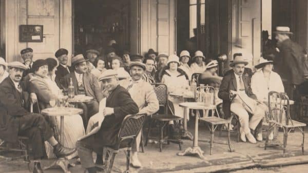 FRANCE - CIRCA 1925s-1935s: Bustling French cafe terrace scene with men and women seated outdoors, enjoying drinks and conversation.
