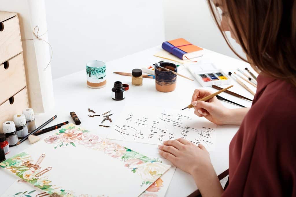 Girl writing "fly me to the moon let me play among the starts" in cursive